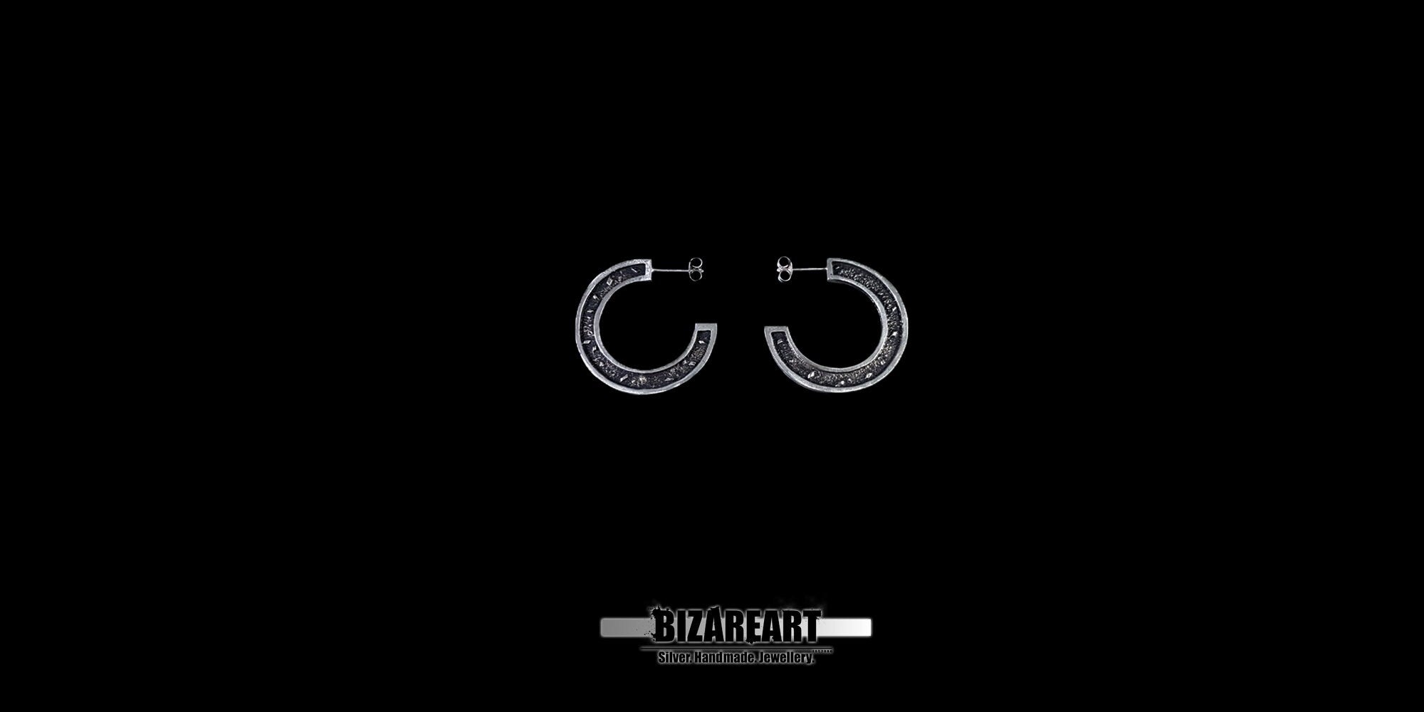 A wide-angle product shot of the circular sector earrings on a black backdrop, emphasizing the sculptural silhouette and metallic luster.