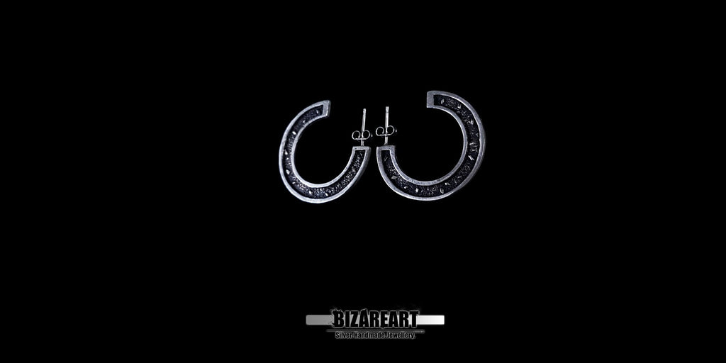 A centered view of the oxidized silver earrings, showcasing the secure stud pin backing and the dark, antique finish of the inner curves.