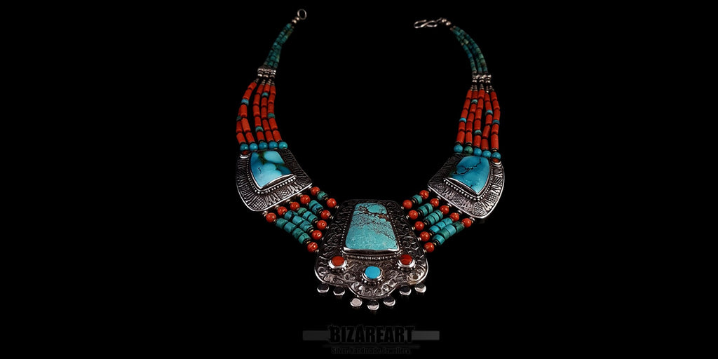 Symmetric front view of a vintage handmade Tibetan necklace featuring a large turquoise pendant, silver embellishments, and five strands of alternating red coral and turquoise beads.