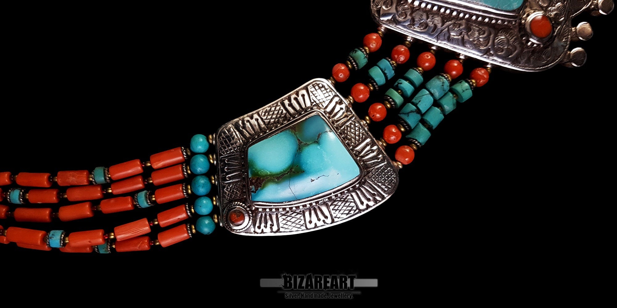 close up 360-degree angle of the vintage Tibetan silver necklace, zooming in on the intricate turquoise sidepiece, red coral strands, and artisan metalwork details against a black background.