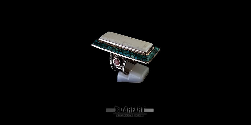 Opposite side angle of the handcrafted Himalayan ring, emphasizing the balance of the turquoise border and the coral inlay on the textured silver band.