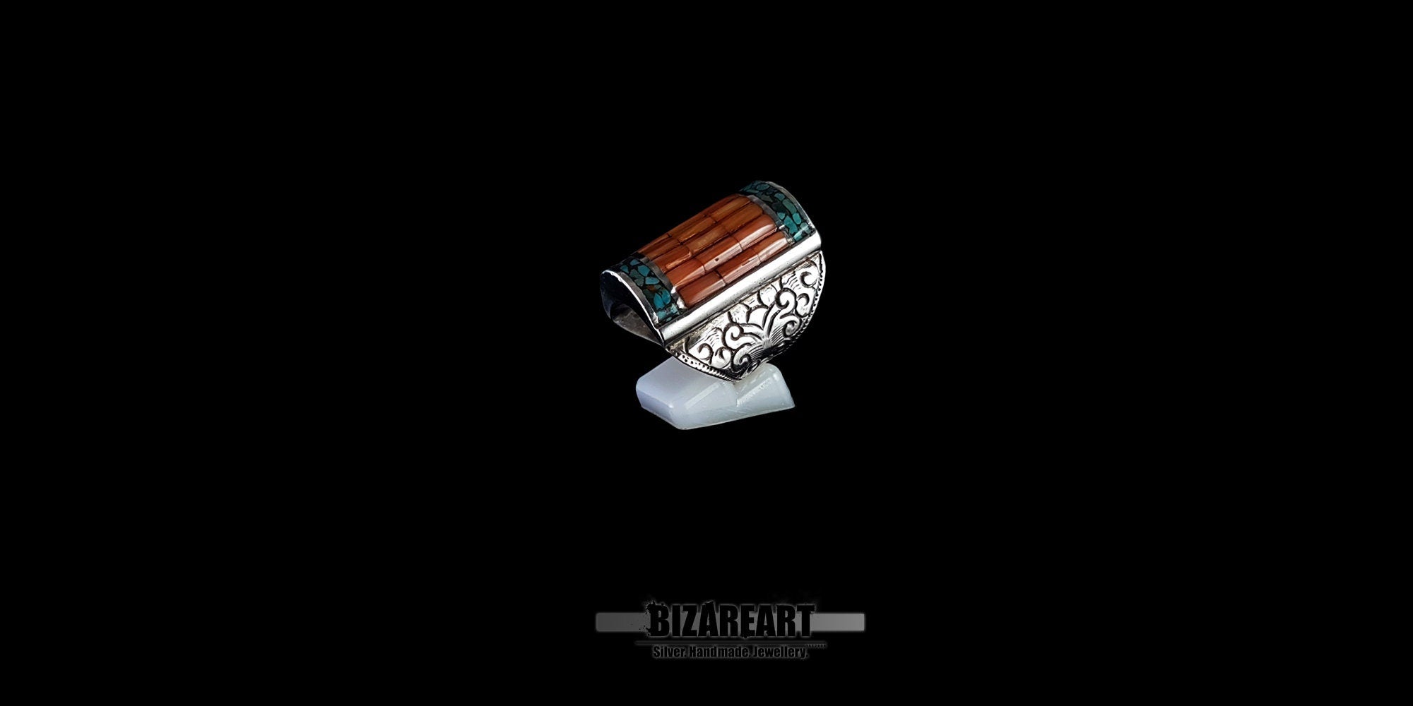 Angled top view of a handcrafted silver Himalayan ring featuring a striking center inlay of parallel red coral pieces bordered by bright turquoise mosaic accents.