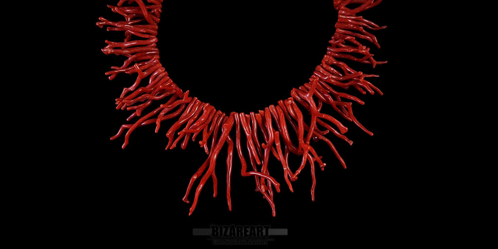 Close-up detail of polished red coral branches on a handmade sterling silver chain necklace