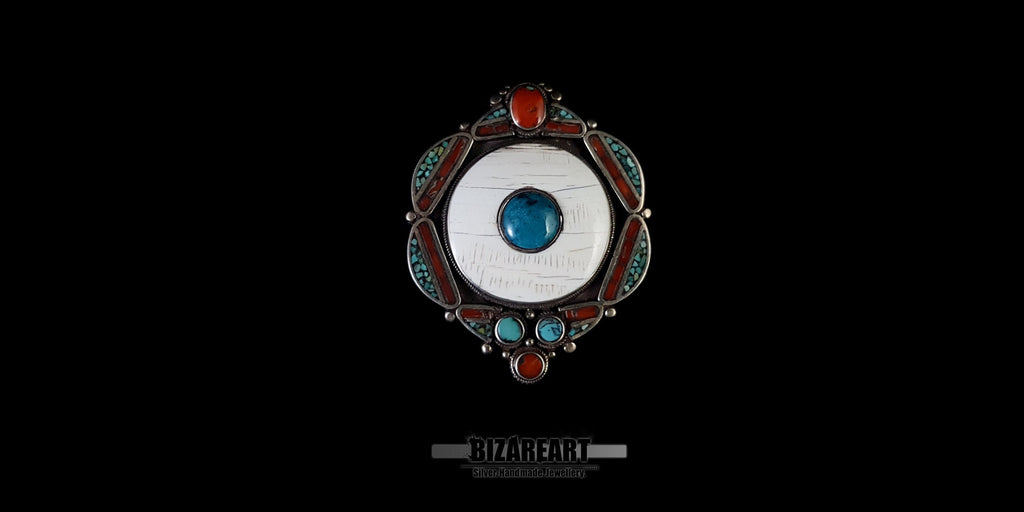 Front view of a large vintage Tibetan silver pendant featuring a central white conch shell cabochon inlaid with a turquoise gemstone.
