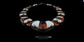 Angled front view of a vintage Nepalese necklace featuring a large inlaid bronze pendant, white Tibetan conch shell segments, and vibrant red coral and turquoise stones against a black background.