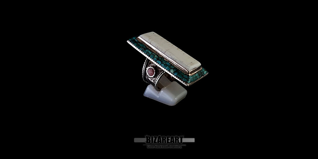 Three-quarter top view of a vintage Himalayan silver ring, highlighting its geometric design, raised conch center, and engraved silver border.