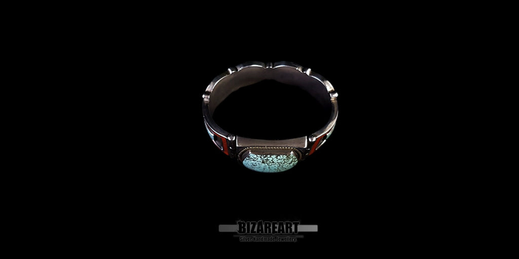 A look inside the cuff of the open bracelet, showing the inner silver lining and the structural construction behind the set stones and mosaic panels. Set against a black background.