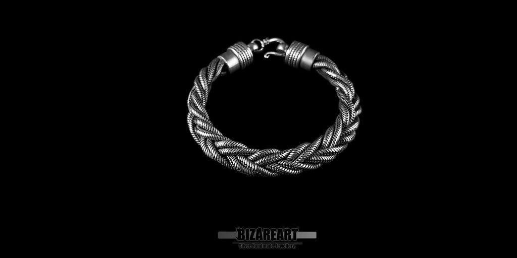 Top-down full view of a chunky silver braided triple rope bracelet against a dark background, showcasing its circular shape and oxidized finish.