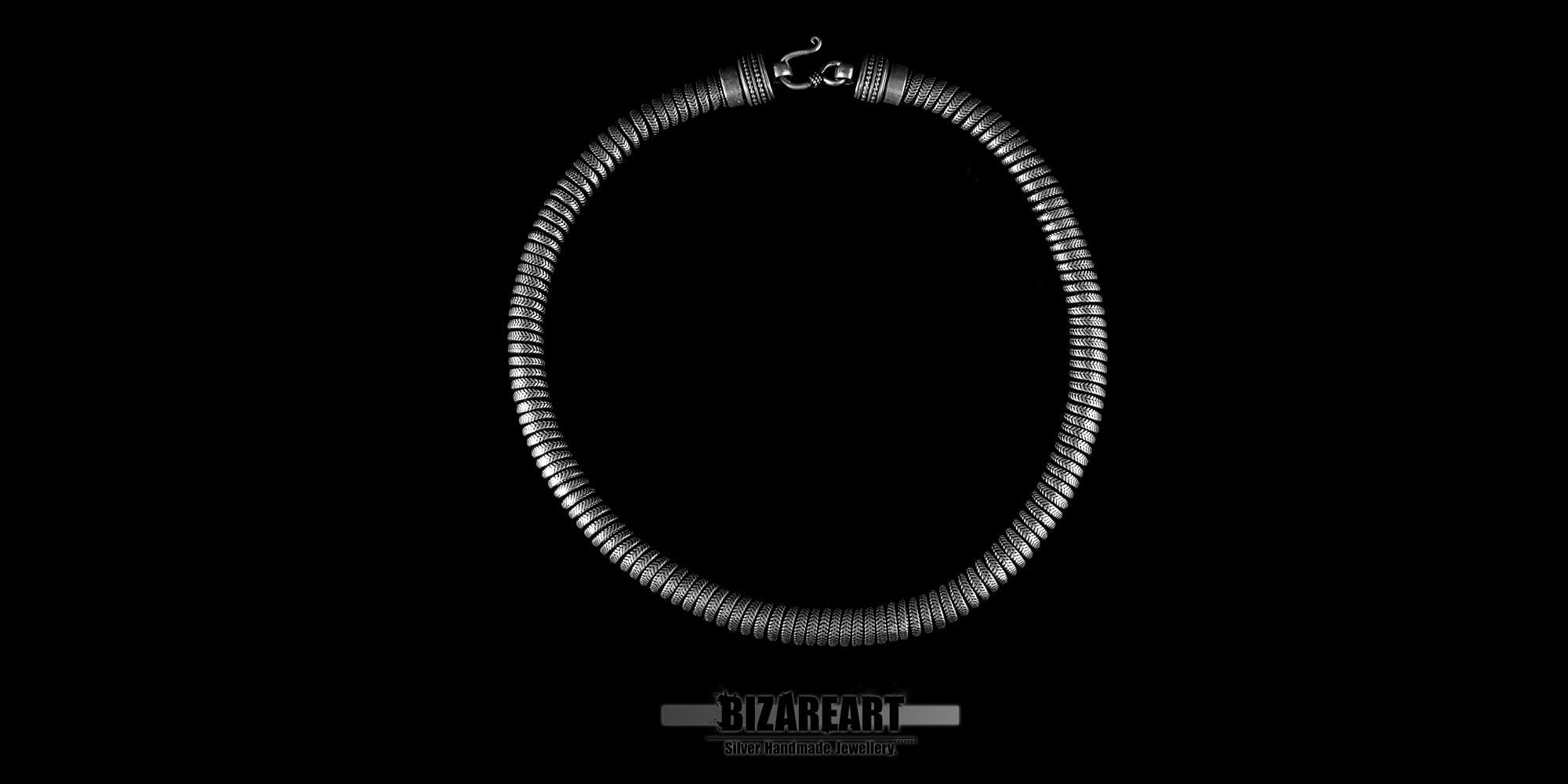 Wide view of a handcrafted Indian silver snake link necklace with a matte finish, displayed in a circular silhouette against a high-contrast black background featuring the Bizareart logo.