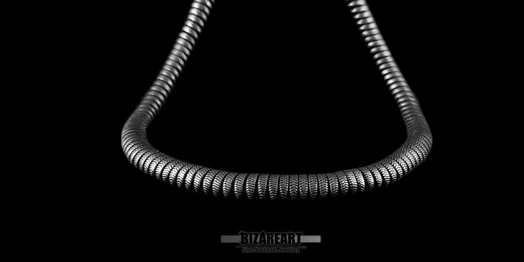 Close-up of the front curve of the silver snake necklace, highlighting the detailed texture of the hand-finished links and the matte, oxidized silver coating.