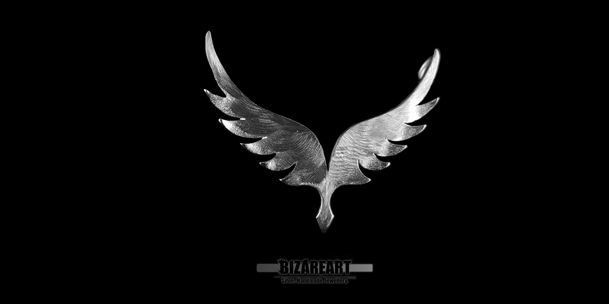 Extreme close-up of the Angel Wings v5.0 pendant showing the detailed feather engraving and the reflective Rhodium-plated surface.
