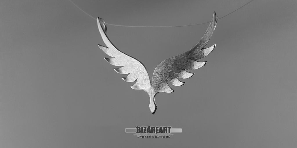 Side-profile view of the silver wing pendant demonstrating the 3D bending deformation and the depth of the sculptural design.