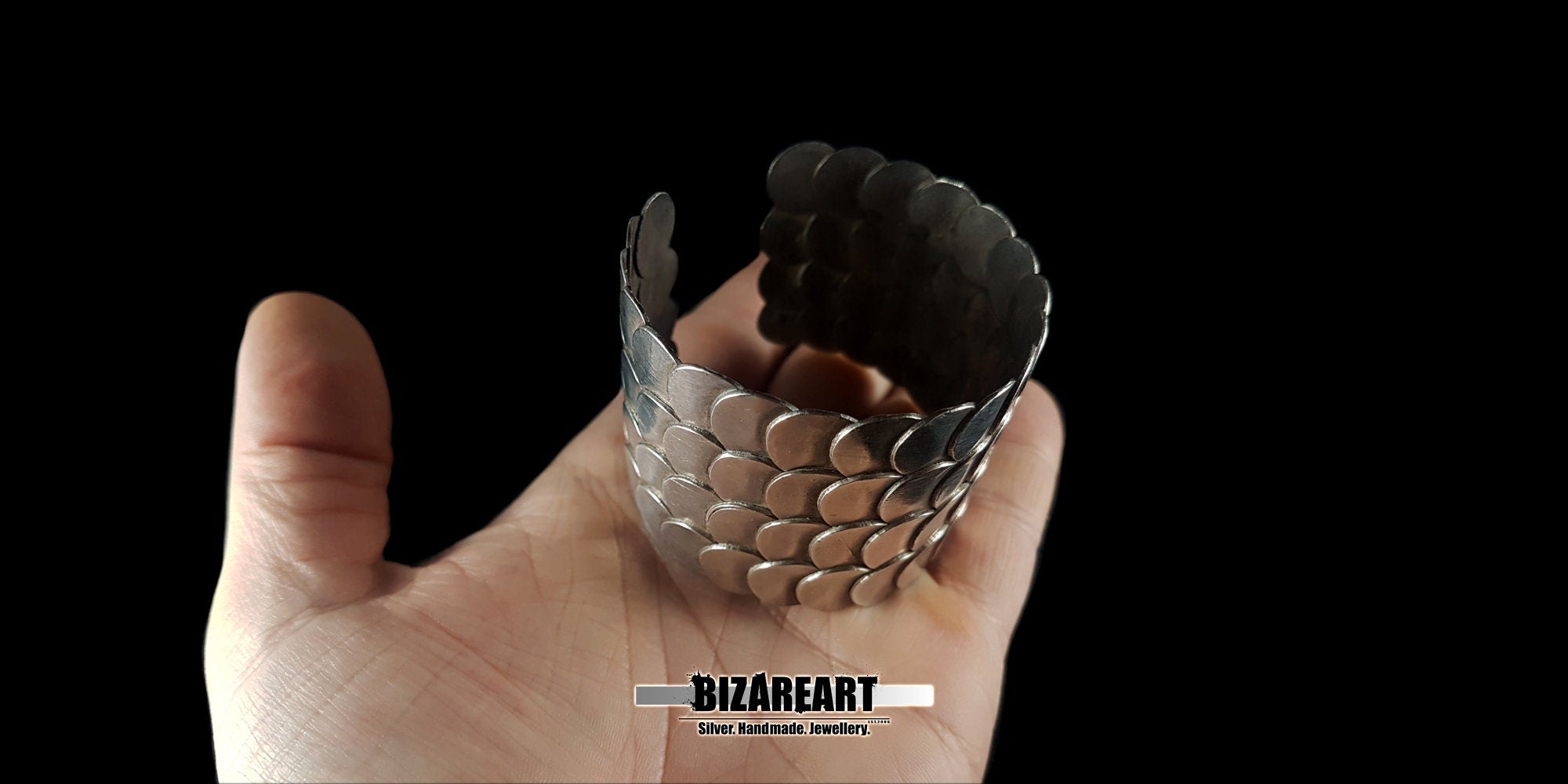 A hand-held shot of the bracelet, providing a real-world scale of the 83g silver piece and its reflective finish.