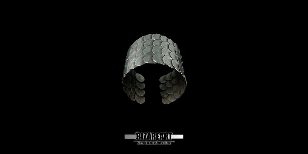 A wide shot of the Remarkable 80 Silver Cuff Bracelet centered against a black background, showcasing the interlocking circular scale design.