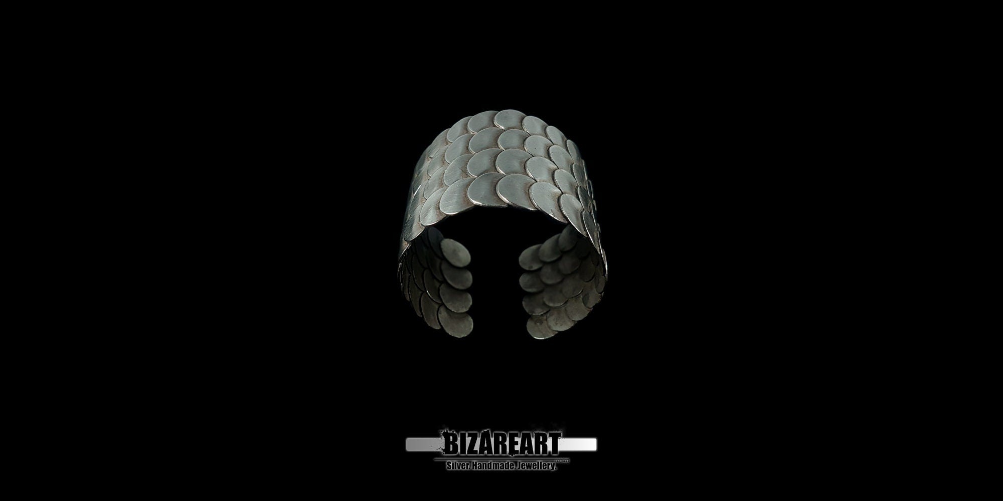 A wide shot of the Remarkable 80 Silver Cuff Bracelet centered against a black background, showcasing the interlocking circular scale design.