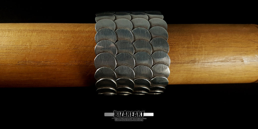 A direct side-profile view on a wooden surface, showing the substantial 6.2 cm width of the silver band.