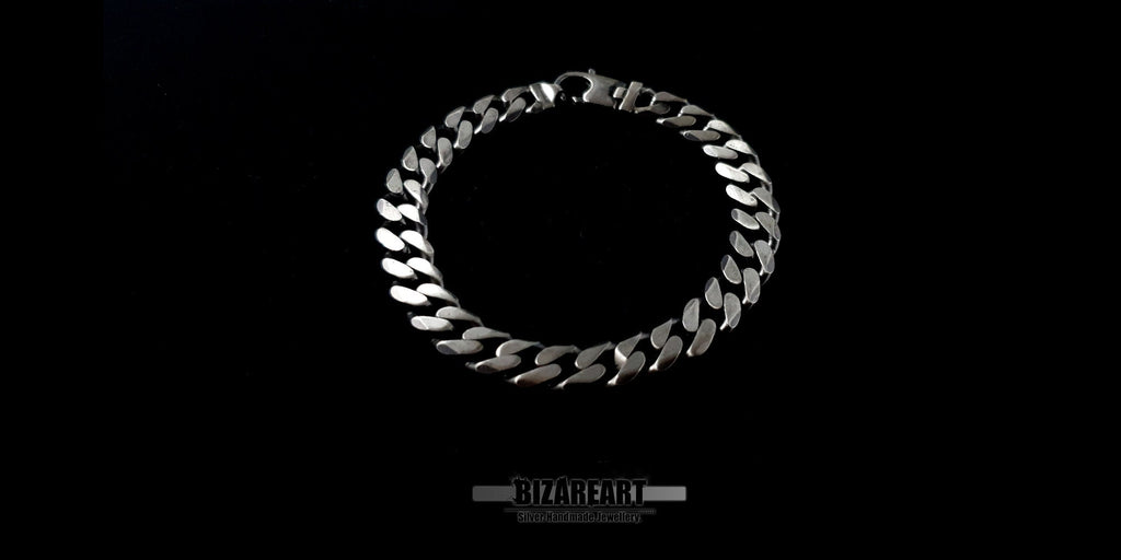Close-up overhead shot of a circular sterling silver chain bracelet highlighting the symmetrical plait and secure hook closure.