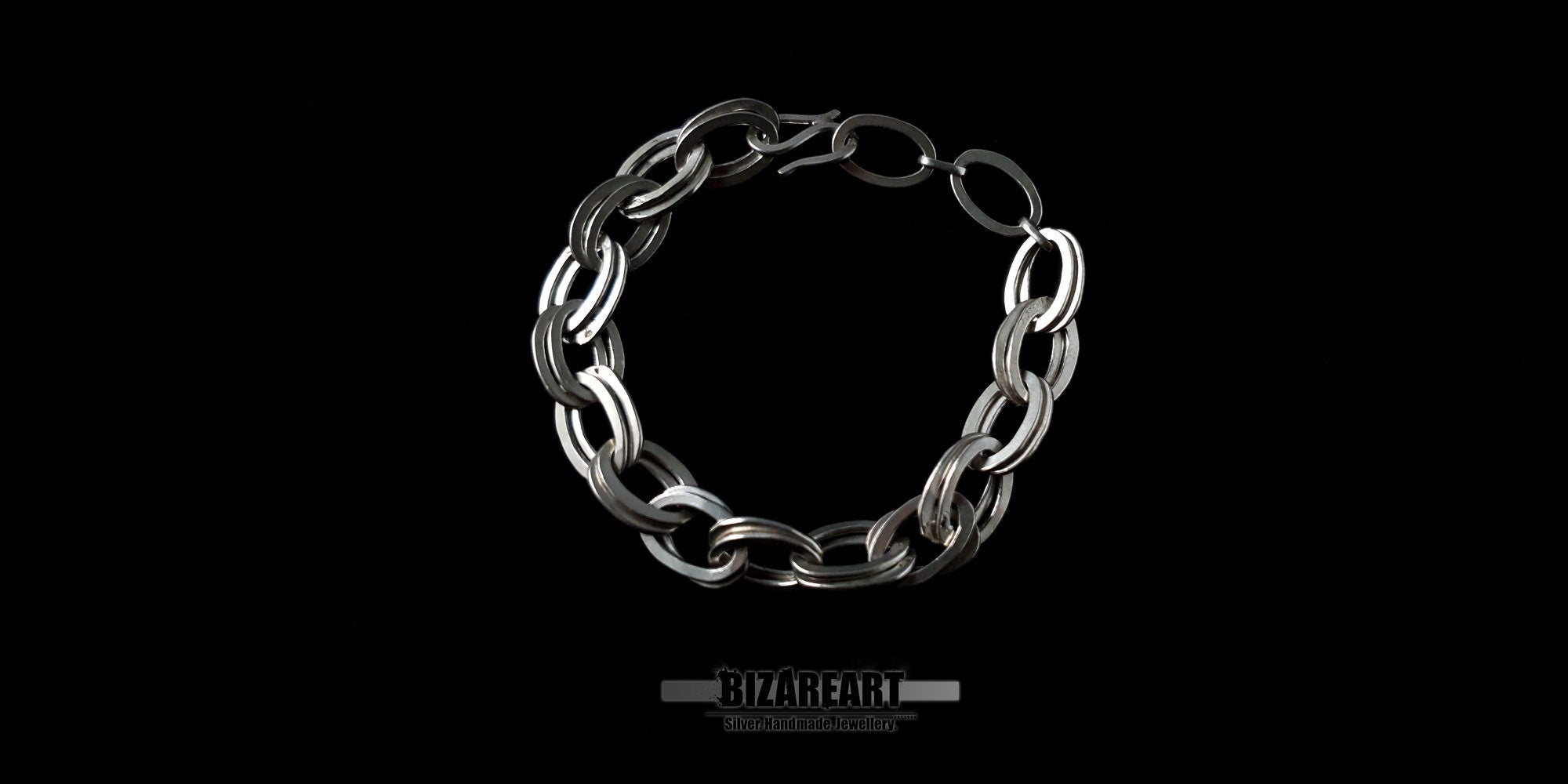 Top-down view of a handcrafted double loop sterling silver chain bracelet with a secure S-hook clasp against a black background.
