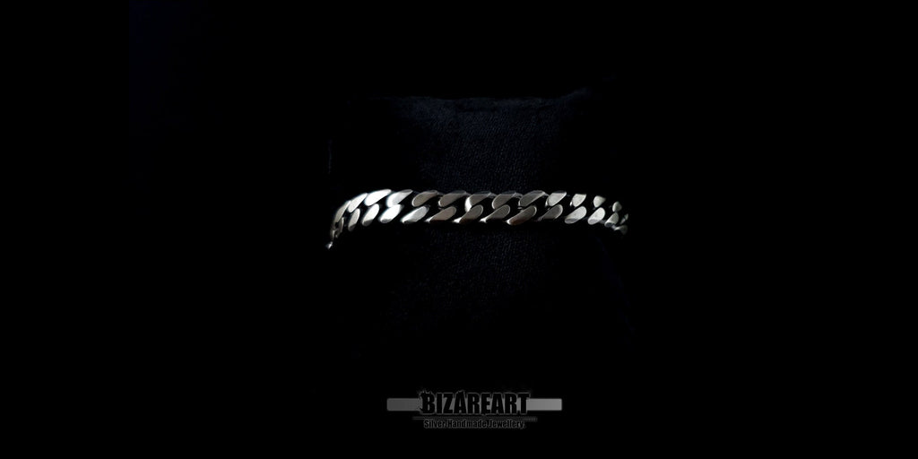 Side profile of the silver curb bracelet resting on a surface, emphasizing the 1.7mm thickness and polished edges.