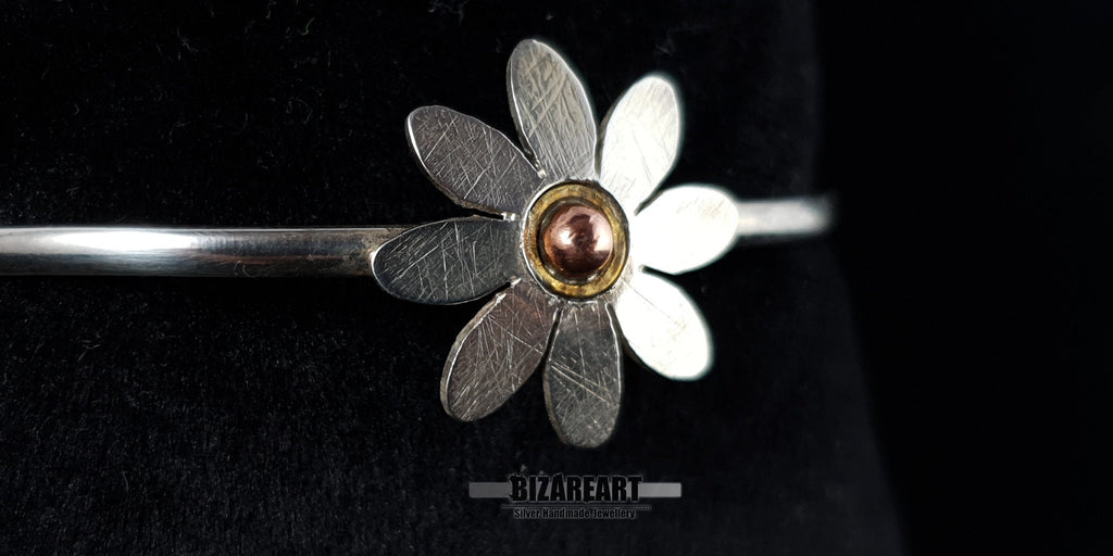 Extreme macro close-up of a hand-finished sterling silver daisy flower charm with a dual-tone copper pink gold center.