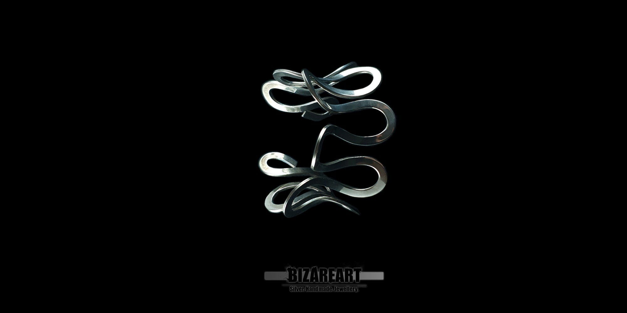 A product photograph displaying the silver cuff bracelet from a slightly elevated angle against a black background. The perspective emphasizes the open, adjustable structure of the piece and the complex, interlocking aesthetic of its polished silver waves.