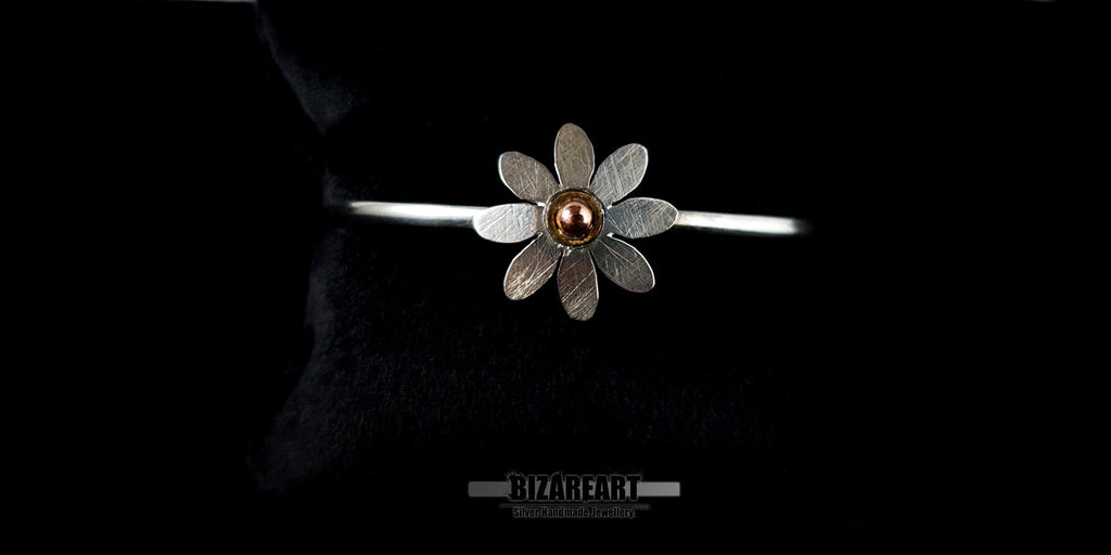 Minimalist sterling silver wire cuff bracelet featuring a mixed-metal copper and gold-plated flower charm.
