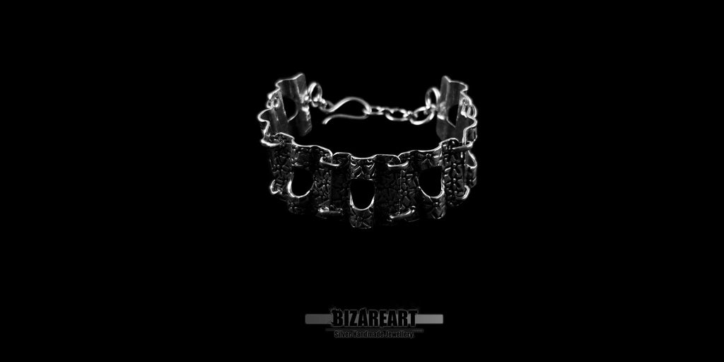 Handcrafted Greek sterling silver panel bracelet with star markings, displayed standing upright against a solid black background.