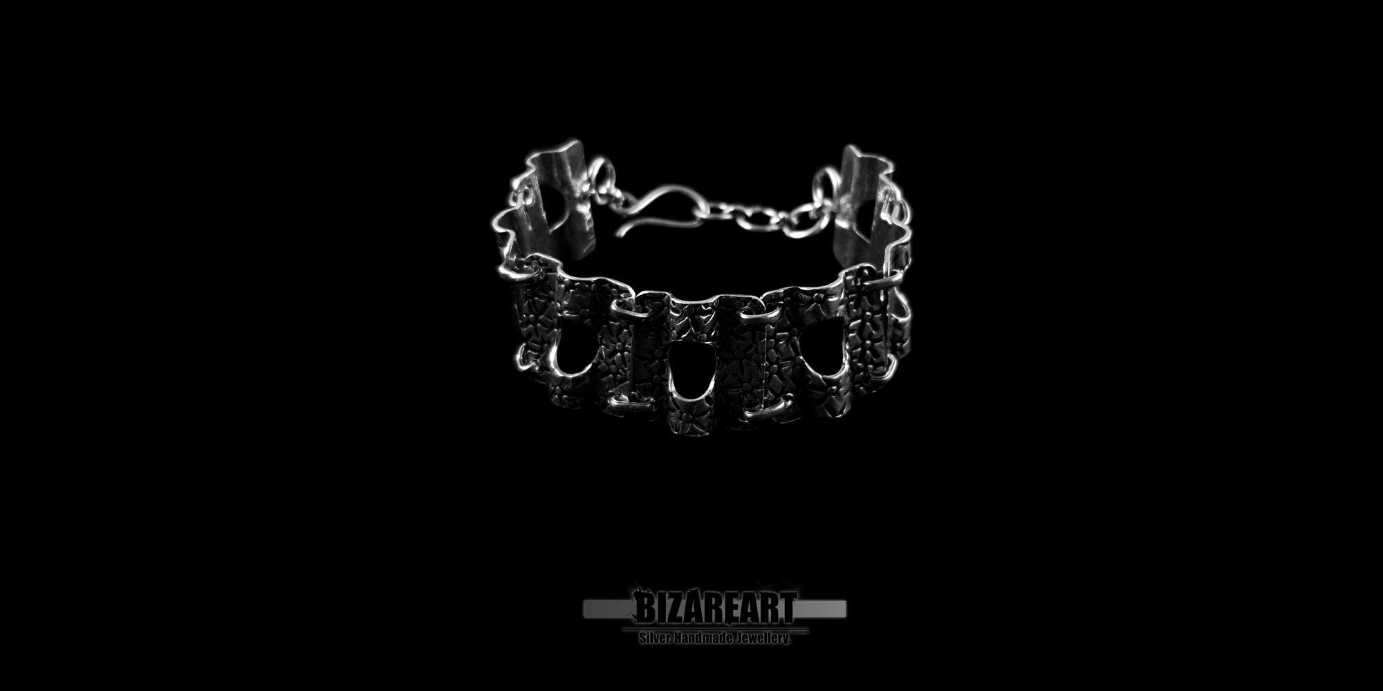 Handcrafted Greek sterling silver panel bracelet with star markings, displayed standing upright against a solid black background.