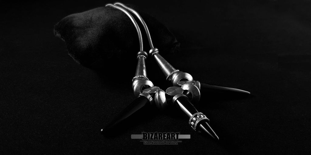 Black Onyx Elegance Necklace by Bizareart featuring three pointed onyx stone spikes and detailed sterling silver loops on a black display pillow.