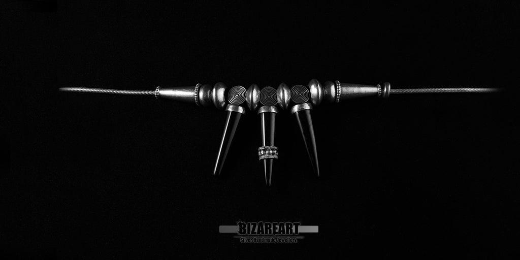 Flat lay presentation of the Bizareart sterling silver gothic necklace with three onyx spikes laid out linearly.