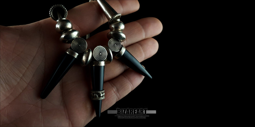 The Black Onyx Elegance Necklace held in a hand to demonstrate the product scale, luxurious weight, and size of the spike pendants.