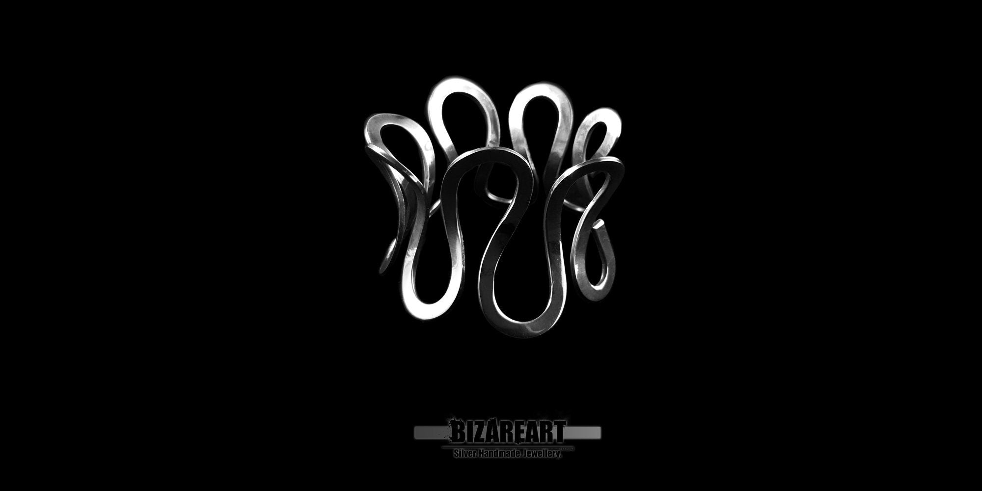 A wide, landscape-oriented product photo showcasing a sculptural sterling silver cuff bracelet against a solid black background. The bracelet features an avant-garde, continuous wavy design with vertical loops that create a crown or ribbon-like effect. The polished silver surface reflects light, emphasizing its fluid, metallic contours. A small, subtle brand logo reading "BIZAREART" is centered underneath the jewelry.