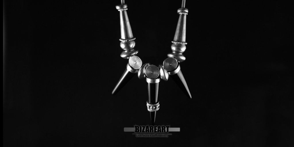 Close-up of a handmade sterling silver statement necklace showcasing three sharp black onyx spike gemstones and intricate silver detailing.