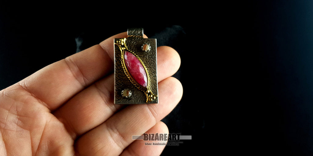 BIZAREART handmade silver and pink ruby pendant held in hand to show size and scale.