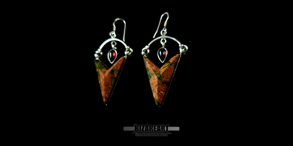 Front-facing view of a pair of Sterling Silver Trillion Unakite earrings featuring large triangular green and pink gemstones with small teardrop garnet accents, set against a black background.