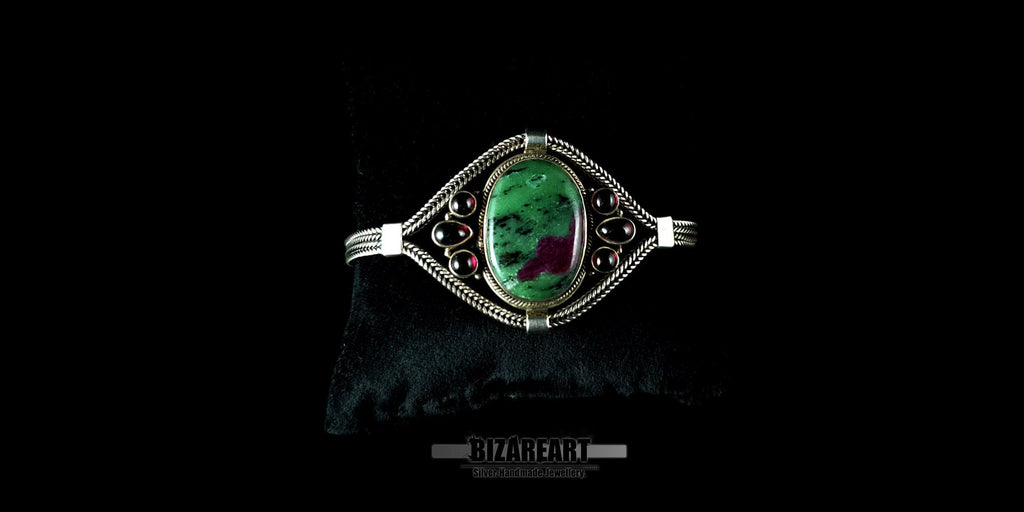 Ruby Zoisite and garnet sterling silver statement bracelet displayed on a black jewelry pillow.