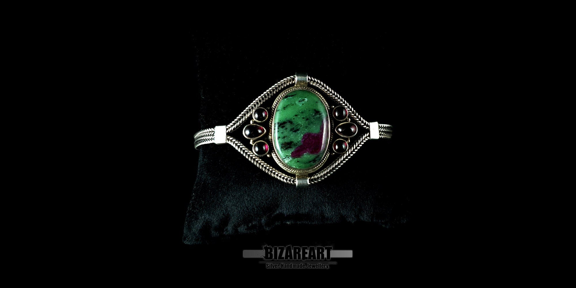 Ruby Zoisite and garnet sterling silver statement bracelet displayed on a black jewelry pillow.