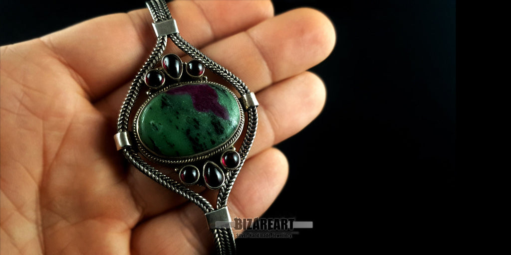 Close-up of the large Ruby Zoisite and garnet silver bracelet being held in a hand to show size and scale.