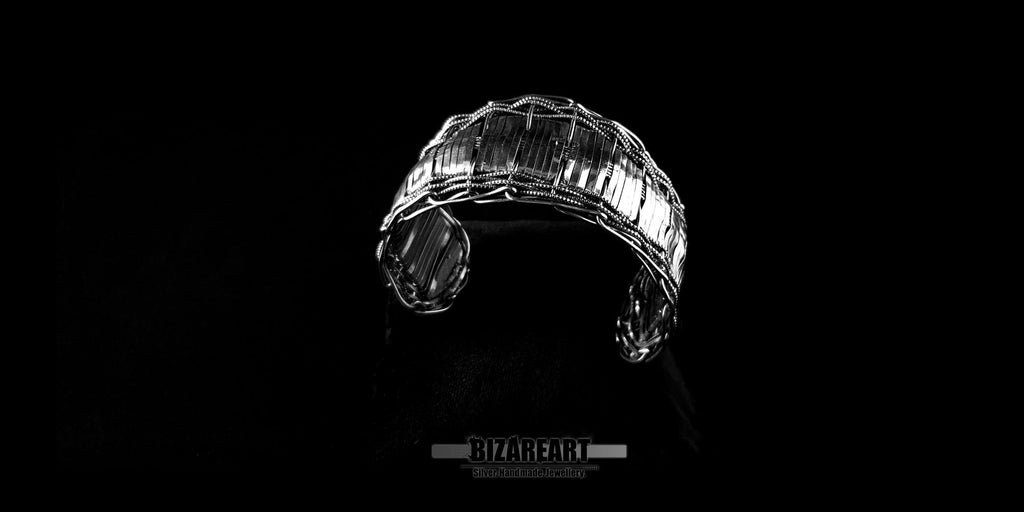 Overhead view looking down into the open section of the silver bangle, showing its structured yet flexible architectural silhouette.