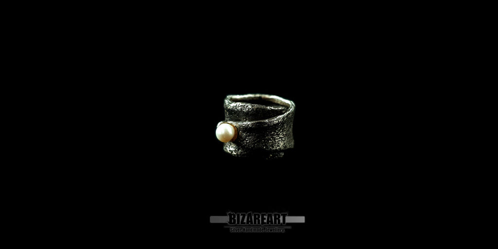 Side view of a handmade Bizareart wrap ring in oxidized sterling silver with a raw, sculptural texture and a single white freshwater pearl set against a black background.