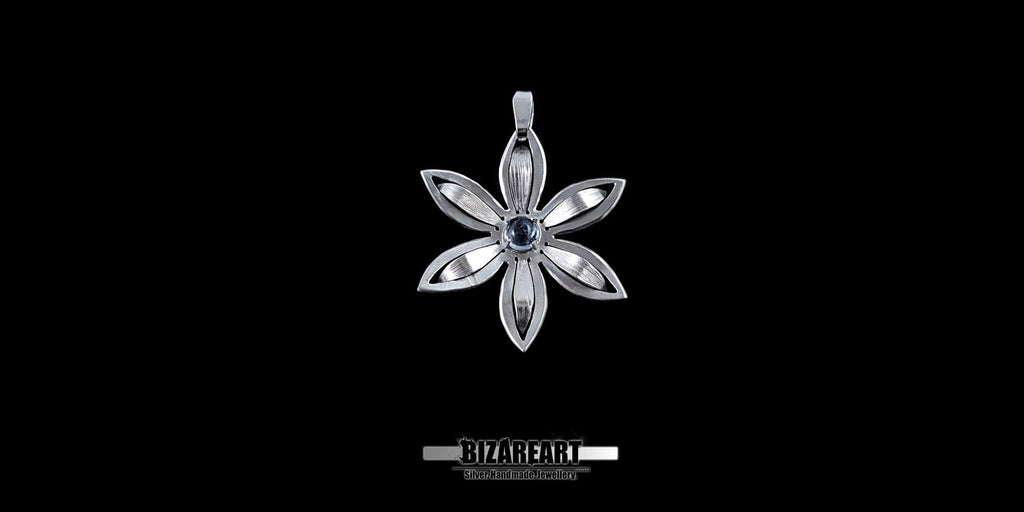 Minimalist silver flower necklace charm with detailed petal engravings and a natural blue gemstone.