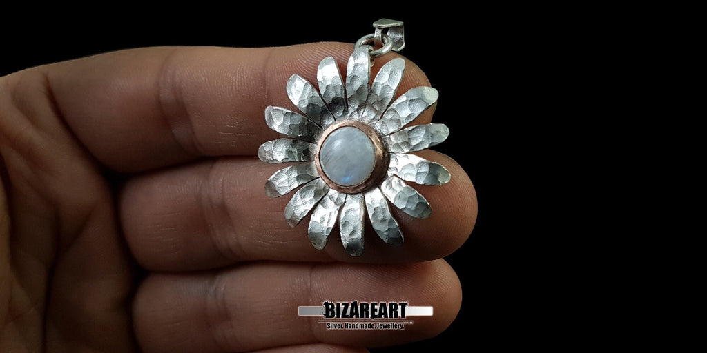 A person holding the large handmade sterling silver moonstone daisy pendant in their hand to show the actual size, scale, and daily wearability.
