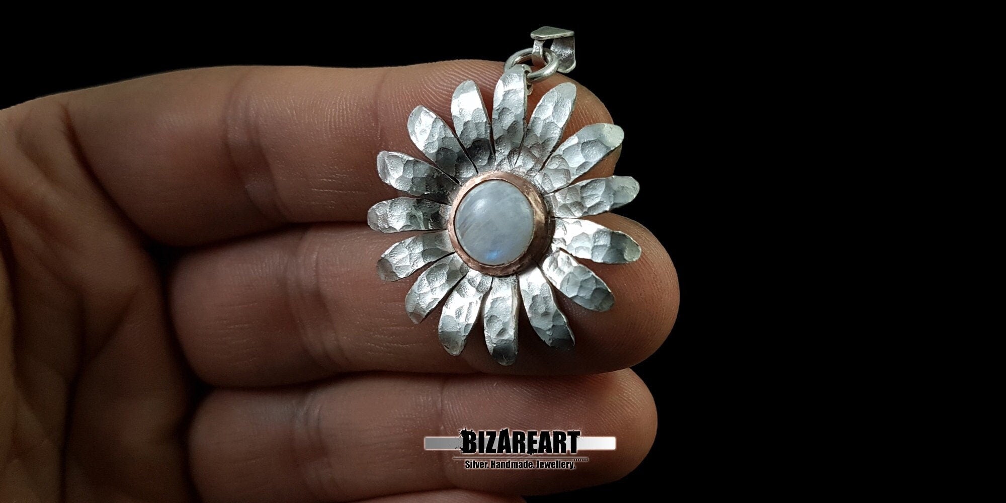 A person holding the large handmade sterling silver moonstone daisy pendant in their hand to show the actual size, scale, and daily wearability.