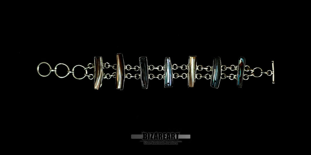 Top view layout of a sterling silver bar bracelet laid flat, showcasing the alternating hoop links and custom bezel-set organic gemstones.