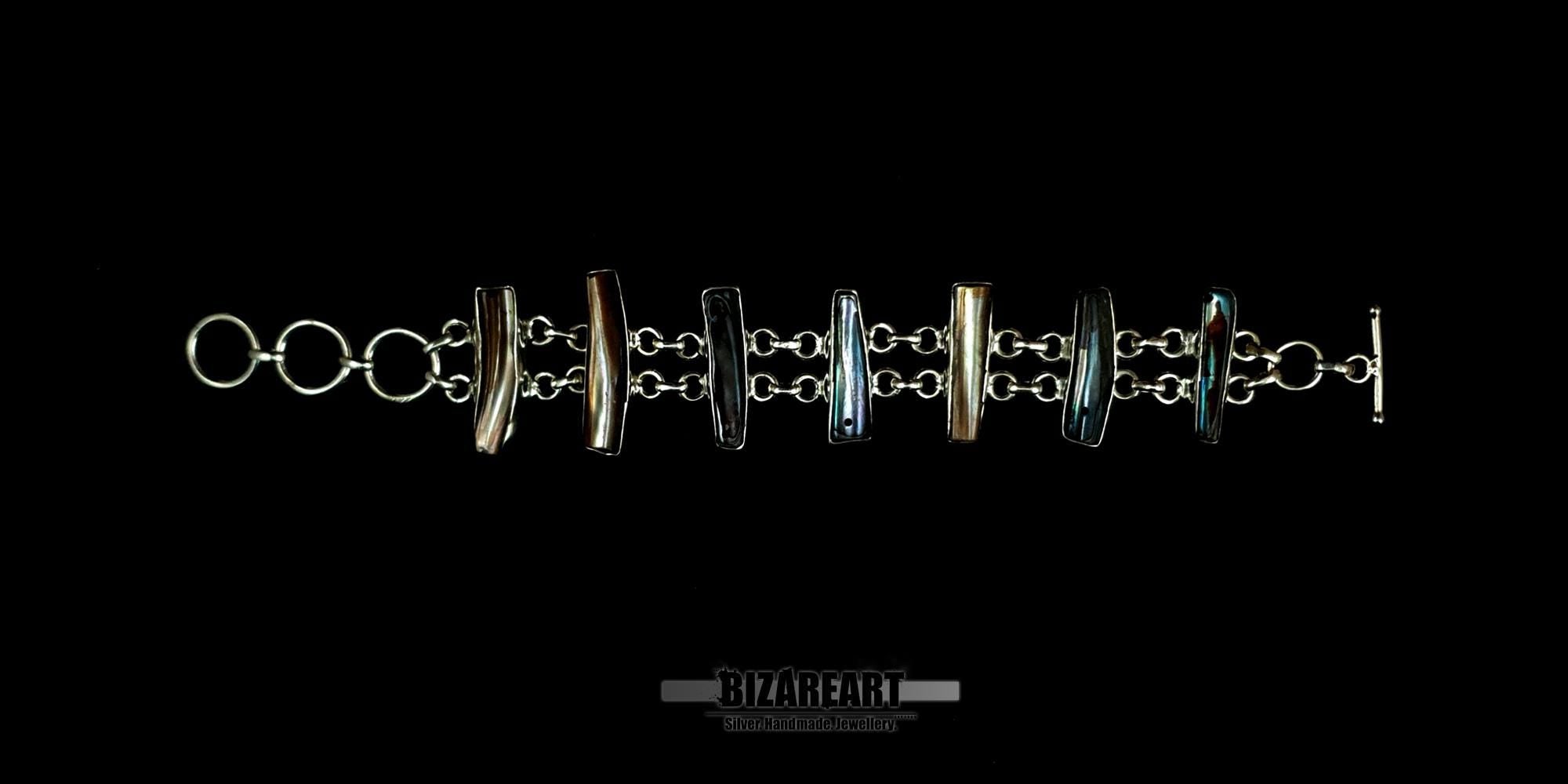 Top view layout of a sterling silver bar bracelet laid flat, showcasing the alternating hoop links and custom bezel-set organic gemstones.