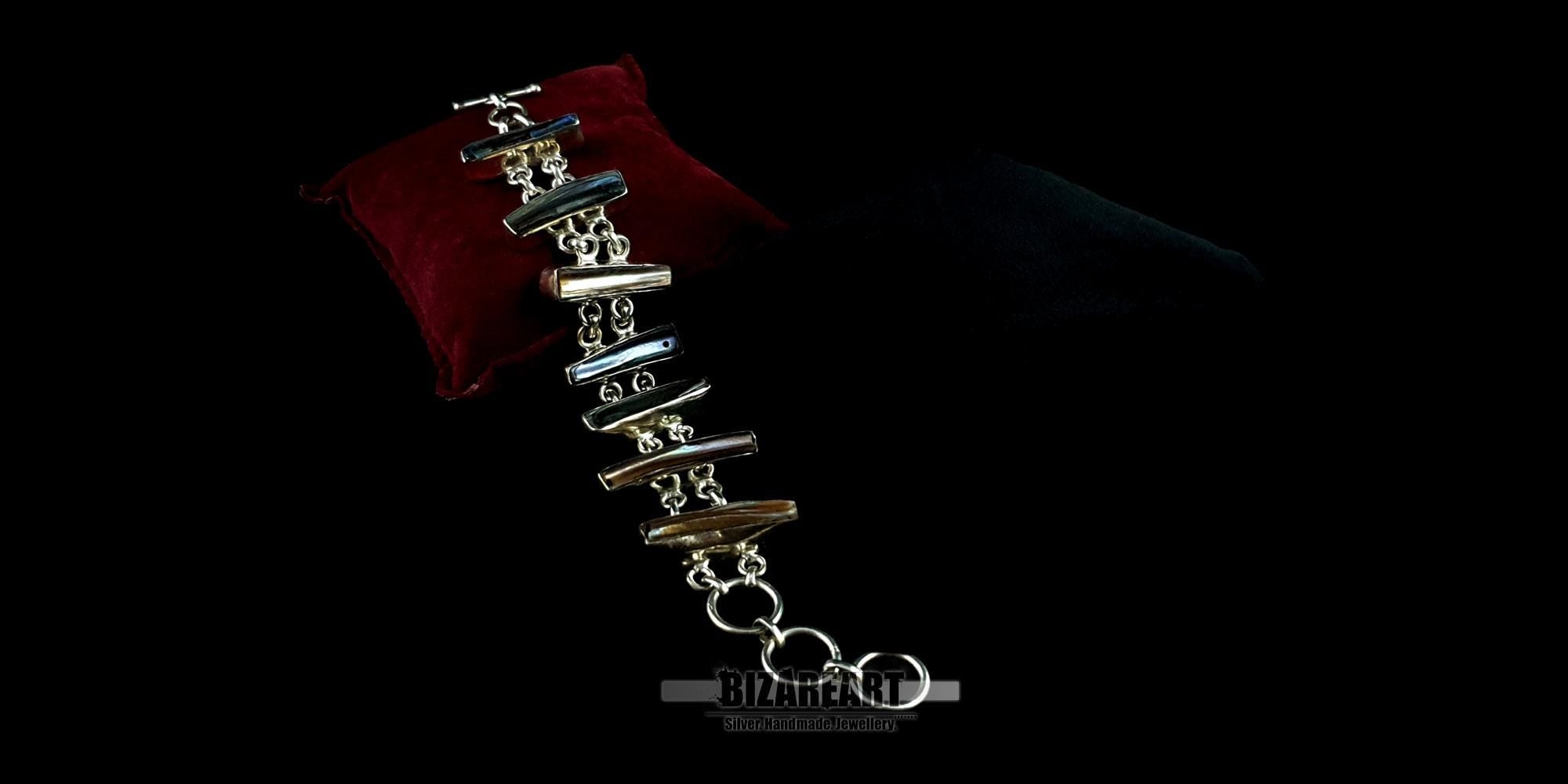 Detailed flat-lay of a handmade 925 silver bracelet with seven distinct bar-cut baroque pearls showing unique color play and a toggle closure.