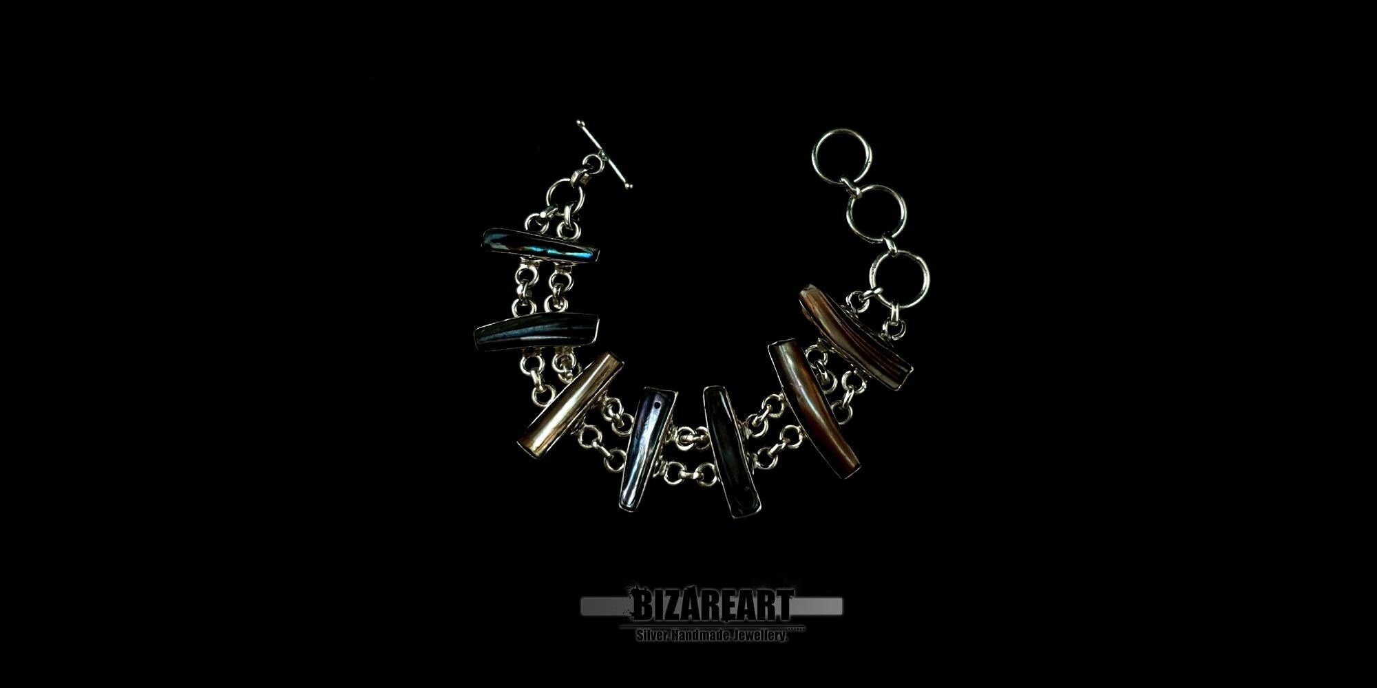 Handmade silver toggle bracelet featuring seven vertical bar-shaped bezel settings with iridescent baroque pearls on a black background Bizareart