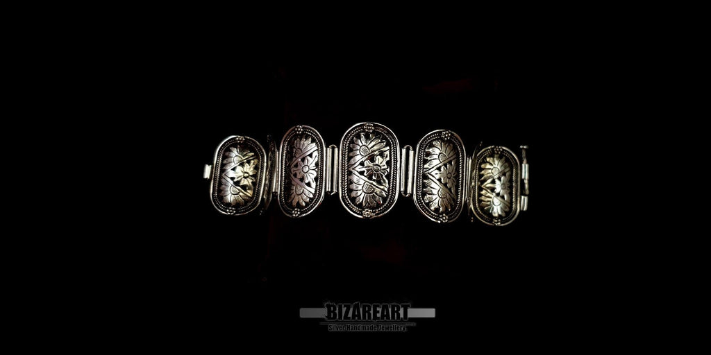 Distant view of the handmade silver floral link bracelet laid flat against a solid black background.
