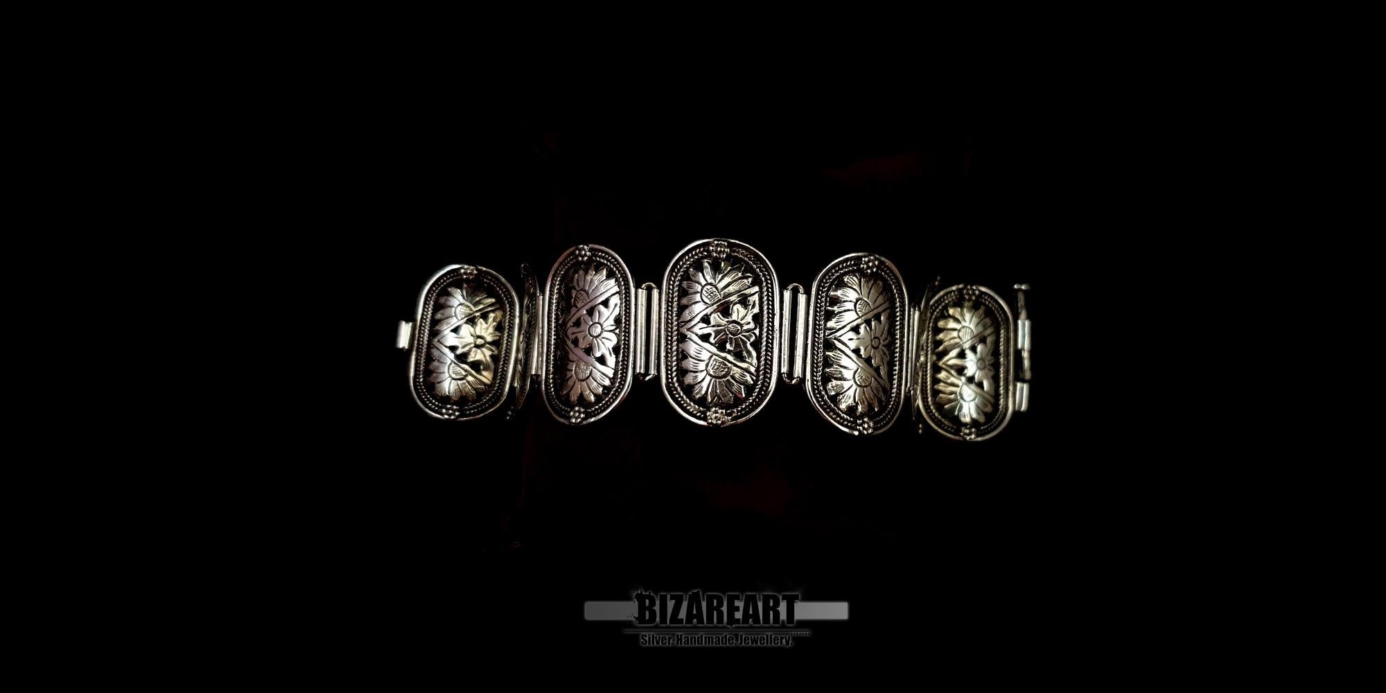 Distant view of the handmade silver floral link bracelet laid flat against a solid black background.