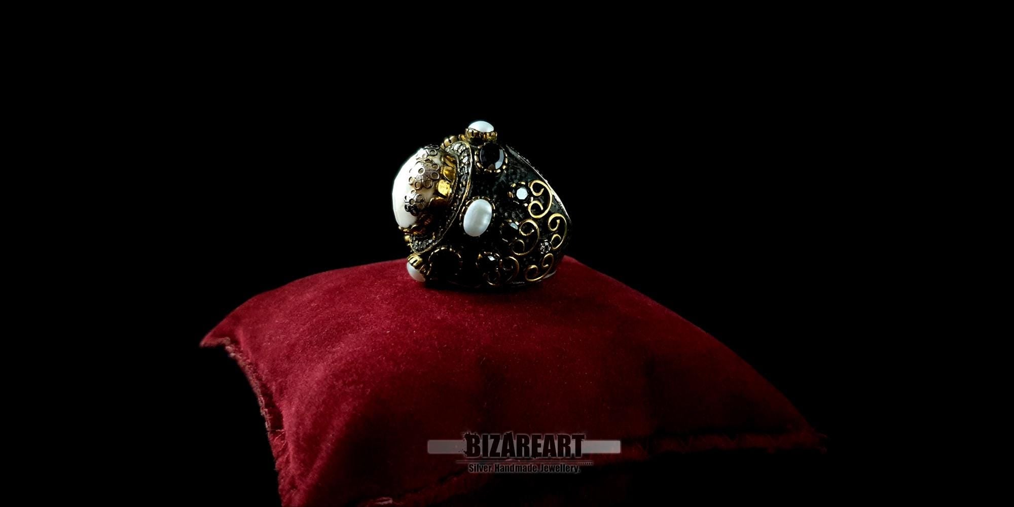 Angled shot of an ornate silver and gold-plated cocktail ring showcasing its substantial, bold design.